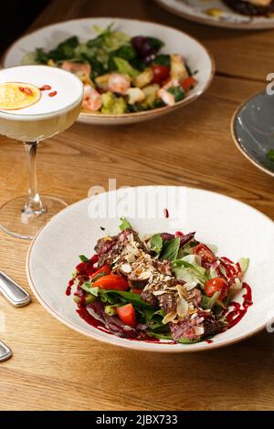 Insalata di vitello e pomodori. Bistecca di manzo con verdure crude mix vista laterale. Carne alla griglia con contorno da vicino. Delizioso piatto principale sul tavolo. Foto Stock