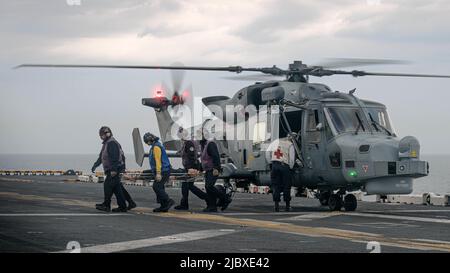 Un elicottero Royal Navy Agusta Wesland AW159 Wildcat prova il trasporto del personale ferito durante un addestramento di risposta medica sul ponte di volo della nave d'assalto anfibio di classe Wasp USS Kearsarge (LHD 3) in durante l'esercizio BALTOPS 22, 7 giugno 2022. BALTOPS 22 è il principale esercizio di attività marittima nella regione baltica. L'esercizio, condotto dalle forze navali statunitensi Europa-Africa, e eseguito dalle forze navali di attacco e supporto NATO, offre un'opportunità di formazione unica per rafforzare le capacità di risposta combinate fondamentali per preservare la libertà di navigazione e sicurezza nel Baltico Foto Stock