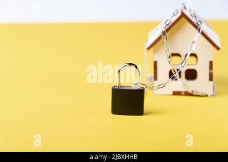Arresto dell'alloggiamento. Casa del castello. Piccola casa giocattolo e una catena con un lucchetto. Sfratto per mancato pagamento. La porta chiusa a chiave della casa. Foto Stock