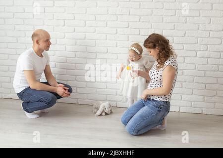 Il bambino con gli apparecchi acustici e gli impianti cocleari gioca con i genitori sul pavimento. Concetto di sordi e riabilitazione e diversità Foto Stock