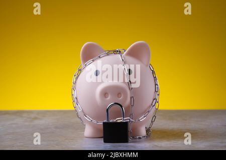 Chiudiosassata. Risparmio bloccato. La banca del piggy è legata con una catena e bloccata. Concetto di protezione dei soldi. Foto Stock