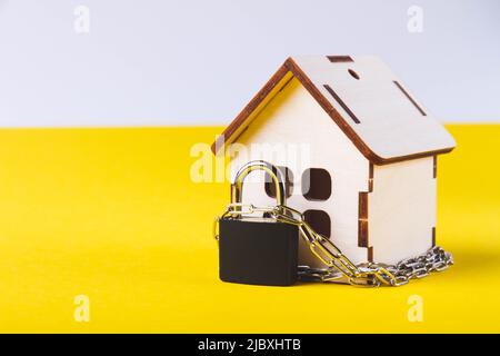 Arresto dell'alloggiamento. Casa del castello. Piccola casa giocattolo e una catena con un lucchetto. Sfratto per mancato pagamento. La porta chiusa a chiave della casa. Foto Stock
