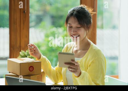 Scatole da imballaggio per il commercio per giovani freelance asiatici. Concetto di e-commerce per le PMI. Foto Stock