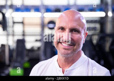 Ritratto di un allenatore di fitness calvo in una palestra sorridendo in macchina fotografica. Foto Stock