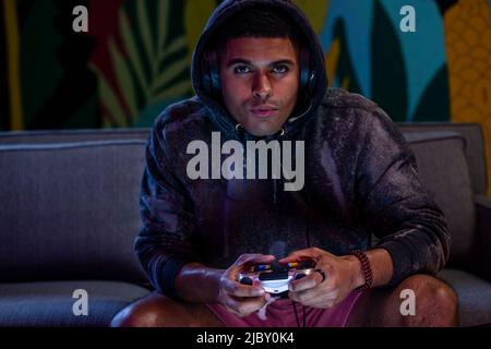 Giovane uomo giocatore in Hood gioco con controller di gioco Foto Stock