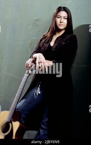 Giovane donna che tiene una chitarra e indossa un crocifisso intorno alla vita Foto Stock