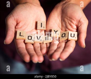 Dettaglio di donna che tiene pezzi sciolti scrabble con la frase “i Love You” scritto sui piccoli blocchi di legno. Amore Foto Stock