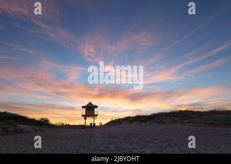 Guardando dalla spiaggia alla torre del bagnino soldato al tramonto Foto Stock