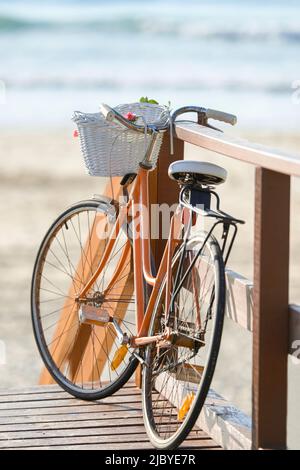 Primo piano della bicicletta della donna appoggiata contro la ringhiera in spiaggia Foto Stock