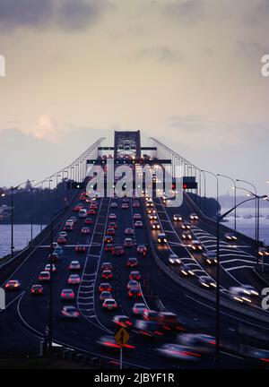 Traffico che scorre in entrambi i sensi sul Ponte del Porto di Auckland al crepuscolo Foto Stock