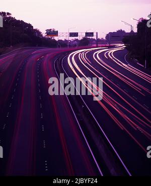 Traffico che scorre in entrambe le direzioni sull'autostrada al tramonto Foto Stock