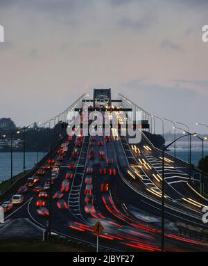 Traffico che scorre in entrambi i sensi sul Ponte del Porto di Auckland al crepuscolo Foto Stock