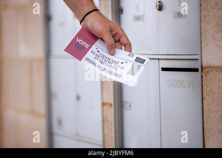 Dettaglio del maschio che pone un messaggio elettorale ufficiale in scrutinio nella mail in uscita presso l'edificio dell'appartamento Foto Stock