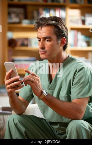 Ispanico medico maschile che pratica la telemedicina dal suo ufficio domestico, parlando con il paziente in videochiamata Foto Stock