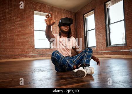 Ritratto di un giovane etnia elegante che indossa un visore VR in uno spazio vuoto Foto Stock