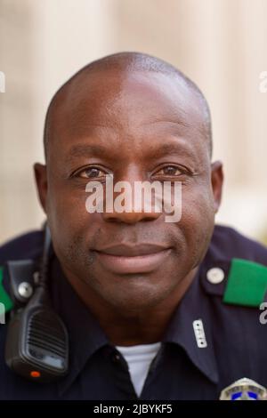 Primo piano Ritratto dell'ufficiale di polizia in uniforme seduto all'esterno guardando la fotocamera sorridendo Foto Stock