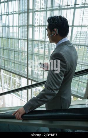 Imprenditore cinese azienda cellulare su di escalator Foto Stock