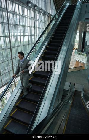 Imprenditore cinese azienda cellulare su di escalator Foto Stock