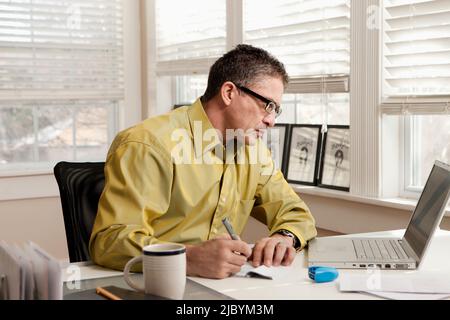 Uomo ispanico pagare le bollette alla scrivania Foto Stock