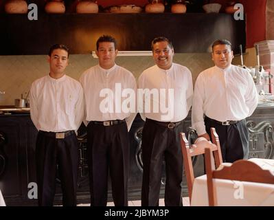 Quattro uomini stavano in piedi in fila in ristorante Foto Stock