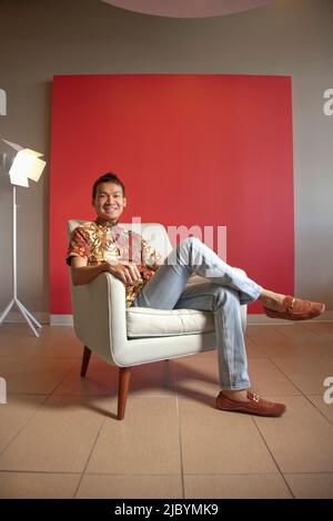 Malese sorridente uomo seduto in poltrona Foto Stock