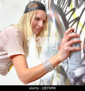 Donna caucasica che tagga il muro con graffiti Foto Stock