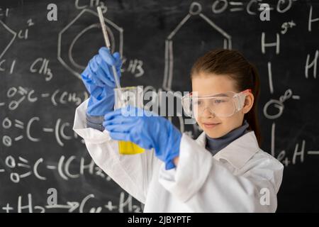 bambino scienziato con vetri in camice da laboratorio con fiasca chimica, piccolo studente su lezione di chimica in laboratorio facendo un esperimento, lavagna scuola Foto Stock