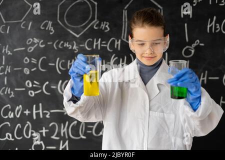 giovane ragazza che fa esperimenti scientifici in laboratorio. studente che fa un esperimento chimico mentre fa l'analisi e la miscelazione del liquido in fiasche di vetro a. Foto Stock