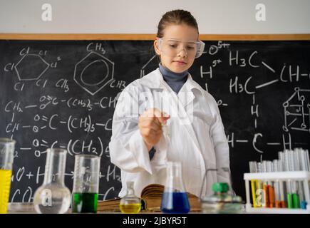 Studentessa che conduce esperimenti chimici in laboratorio scolastico, esperienza scientifica in classe chimica per gli scolari, istruzione e scienza Foto Stock