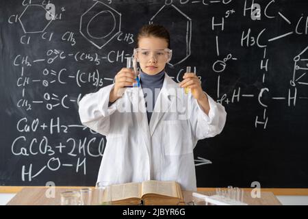 Studentessa femmina che conduce esperimento di chimica. Piccolo studente su lezione di chimica in laboratorio. Esperimenti di scienza in attività in aula Foto Stock