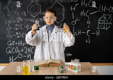 studentessa che conduce esperimento di chimica. piccolo studente su lezione di chimica in laboratorio. esperimenti di scienza in attività di classe Foto Stock