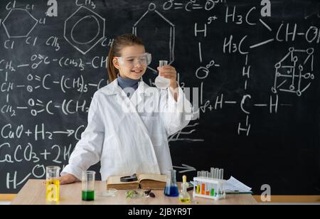 Esperimenti in un laboratorio di chimica. Studente piccolo serio che conduce un esperimento in laboratorio. Ragazza fa un esperimento chimico a lezione Foto Stock