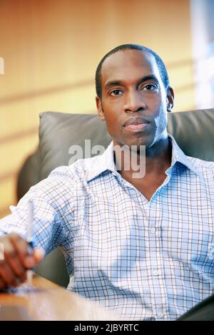 Grave African American businessman seduto alla scrivania Foto Stock