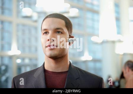 Imprenditore ispanica indossando vivavoce del dispositivo cellulare Foto Stock