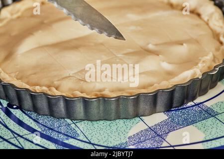 Lo chef prepara delle strisce sulla pasta per torte con il coltello prima di cuocere in forno. Primo piano Foto Stock