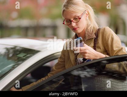 Imprenditrice per arrivare in auto utilizzando il telefono cellulare Foto Stock