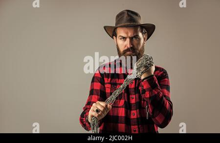 uomo da cowboy brutale con barba e baffi, catena in acciaio, concetto di trappola Foto Stock