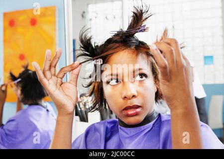 Giovane donna esaminando se stessa nello specchio Foto Stock