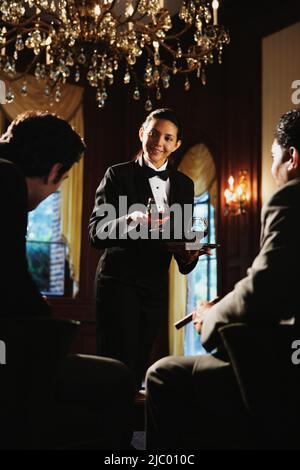 Cameriera in tuxedo che serve bevande Foto Stock