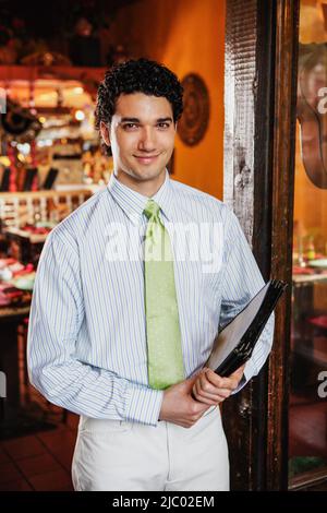 Ritratto di cameriere tenendo premuto menu nel ristorante Foto Stock