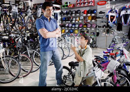 Figlio di accattonaggio padre per la nuova moto in bike shop Foto Stock