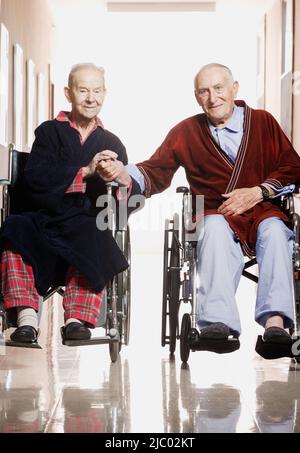 Uomini anziani sorridere per la fotocamera in carrozzina Foto Stock