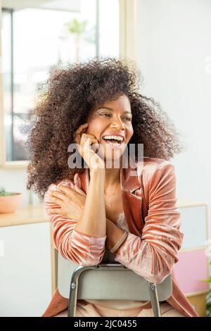 Scatto medio di una donna che guarda la fotocamera sorridendo in uno spazio luminoso. Foto Stock