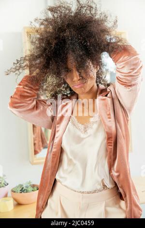 Donna di mezza età corre le mani attraverso i capelli e la porta di fronte al suo viso. Foto Stock