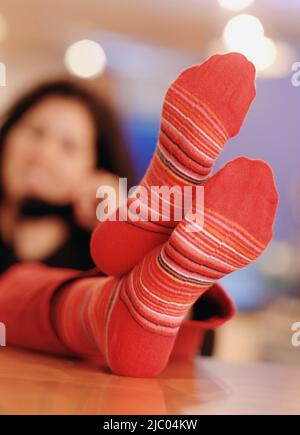Giovane donna con calza i piedi sul tavolo Foto Stock