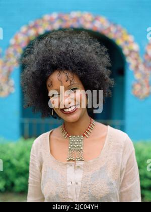 Giovane donna sorridente davanti a casa Foto Stock