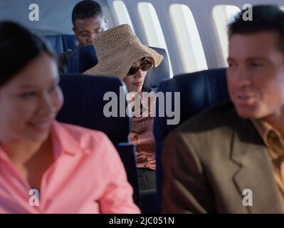 Giovane donna rilassante su aereo con cappello e occhiali da sole Foto Stock
