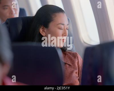 Giovane donna che dorme sul velivolo Foto Stock