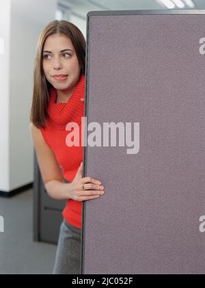 Imprenditrice che spuntavano da dietro la parete di un cubicolo Foto Stock