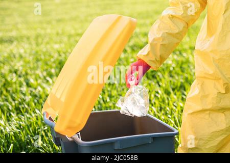 Primo piano la mano della donna gettando via bottiglia di plastica in natura. Danni ambientali causati dai rifiuti di plastica. Foto Stock